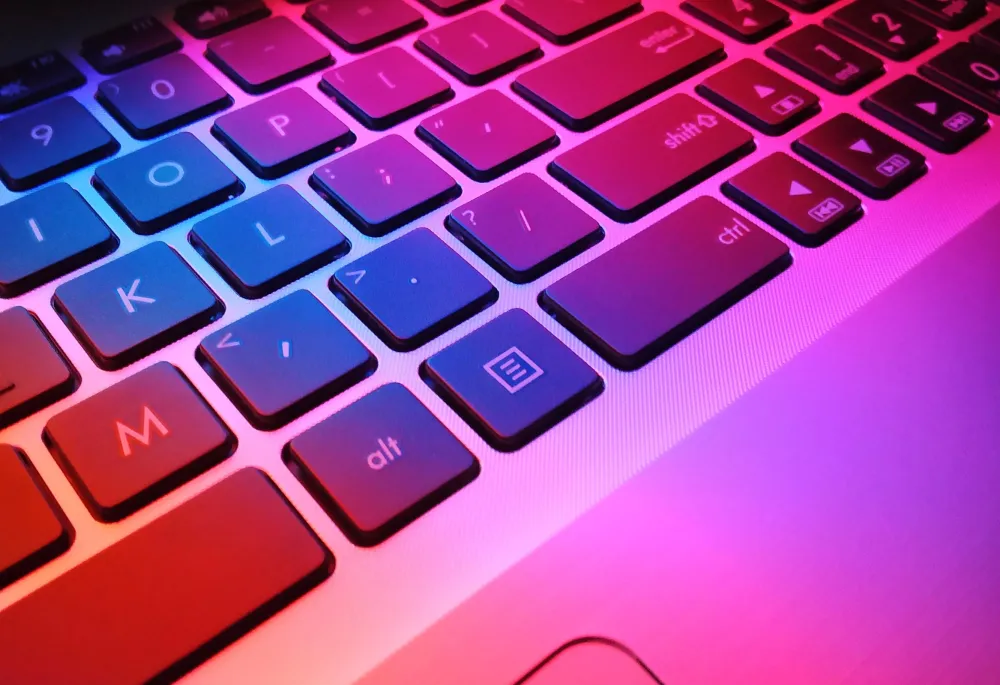A computer keyboard is illuminated with unnatural glowing colors