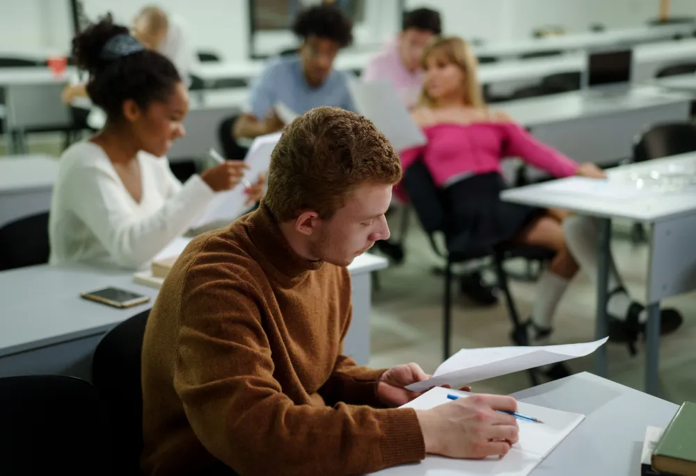 Photo d'une classe présentant 5 étudiants assis en cours, en train de travailler et d'échanger
