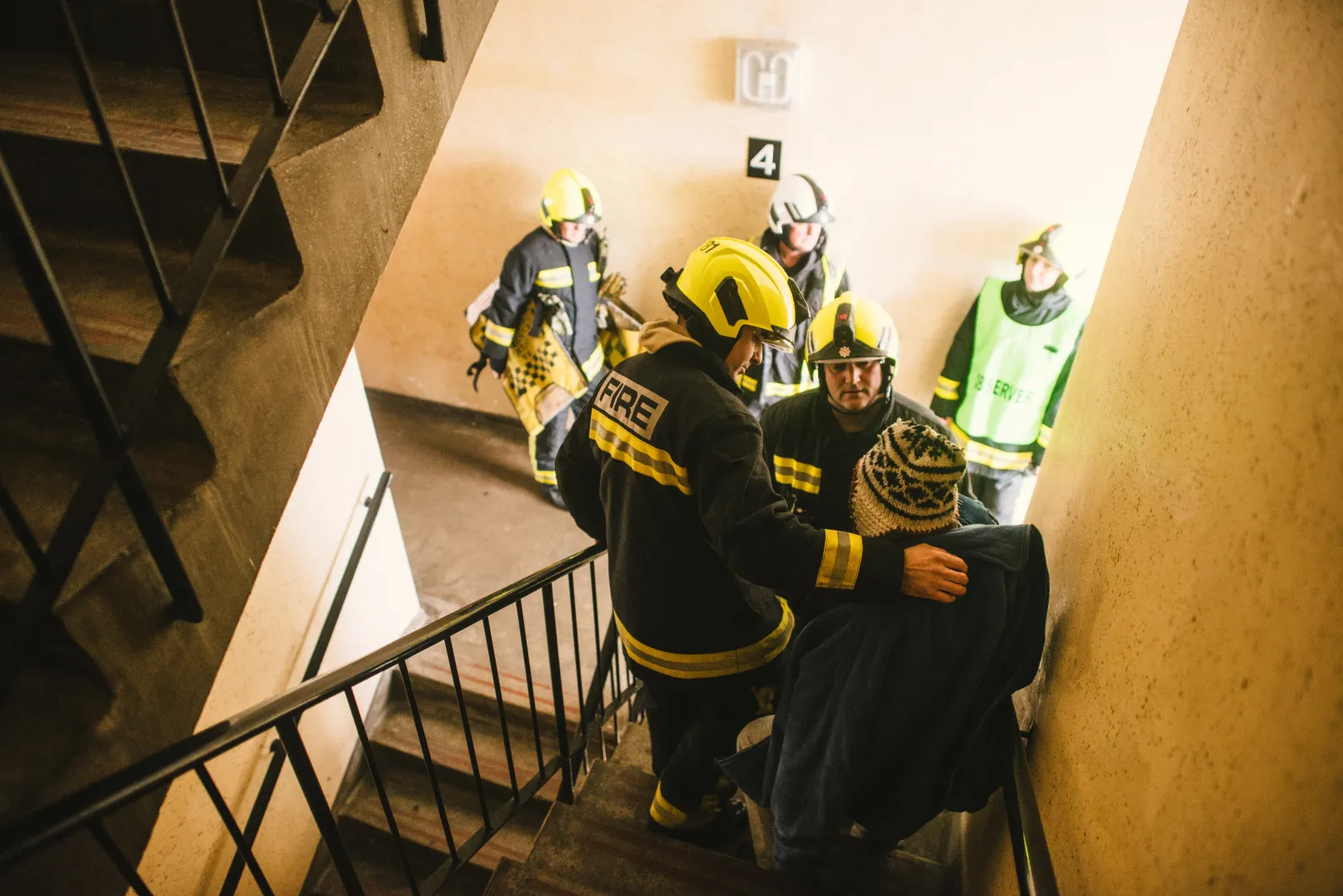Firefighters helping a man on a stairwell, with other members of the team nearby