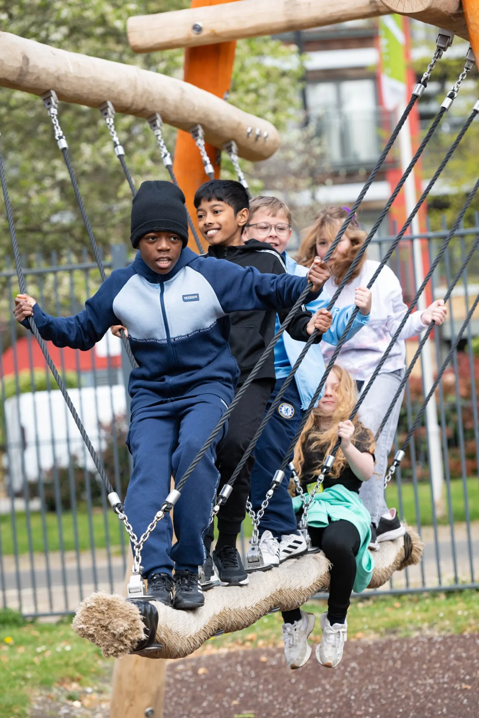 Young people balancing together on a suspended rope at Ellen Brown Adventure Playground in Southwark