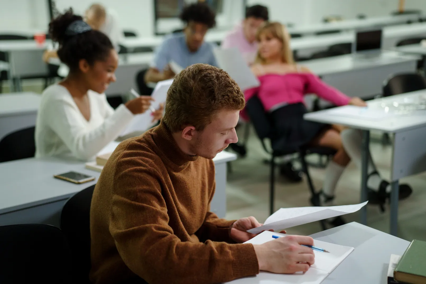 Photo d'une classe présentant 5 étudiants assis en cours, en train de travailler et d'échanger