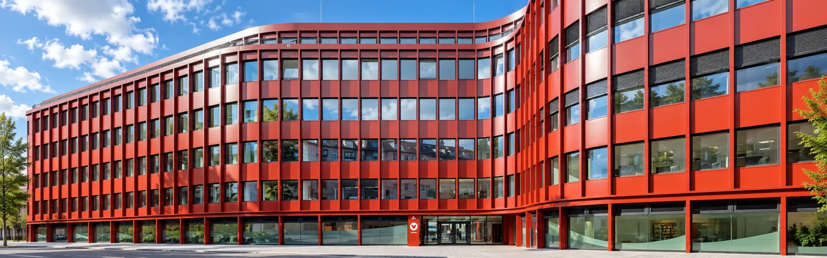 AI-edited image of the red office building in Düsseldorf that houses the joint editorial team of the German consumer advice centres, shown under a partly cloudy blue sky.